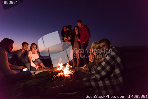 Image of Couple enjoying with friends at sunset on the beach