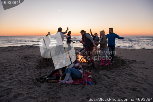 Image of Couple enjoying with friends at sunset on the beach