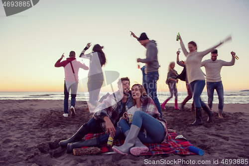 Image of Couple enjoying with friends at sunset on the beach