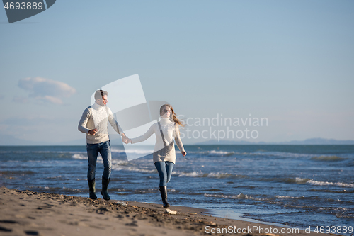 Image of Loving young couple on a beach at autumn sunny day