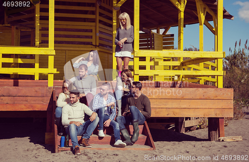 Image of Group of friends having fun on autumn day at beach