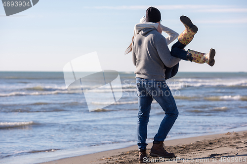 Image of Loving young couple on a beach at autumn sunny day