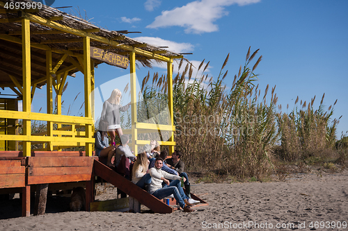 Image of Group of friends having fun on autumn day at beach