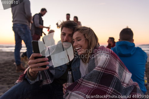 Image of Couple enjoying bonfire with friends on beach