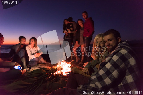 Image of Couple enjoying with friends at sunset on the beach