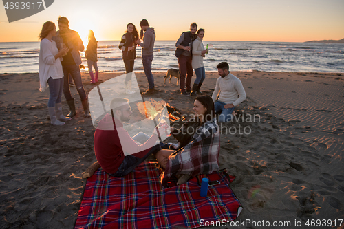 Image of Couple enjoying with friends at sunset on the beach