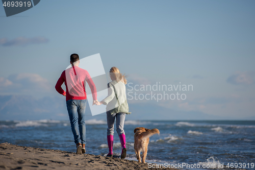 Image of couple with dog having fun on beach on autmun day