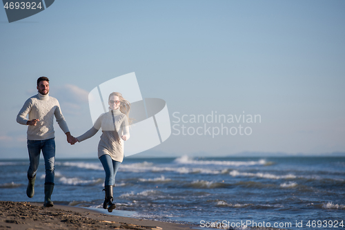 Image of Loving young couple on a beach at autumn sunny day