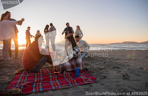 Image of Couple enjoying with friends at sunset on the beach