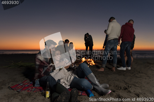 Image of Couple enjoying bonfire with friends on beach