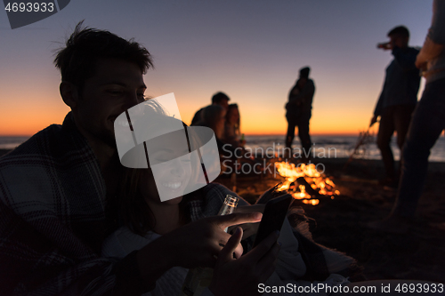 Image of Couple enjoying bonfire with friends on beach