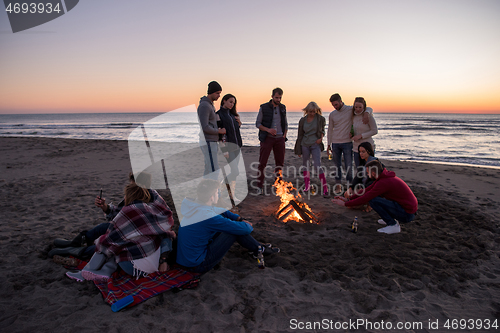 Image of Friends having fun at beach on autumn day