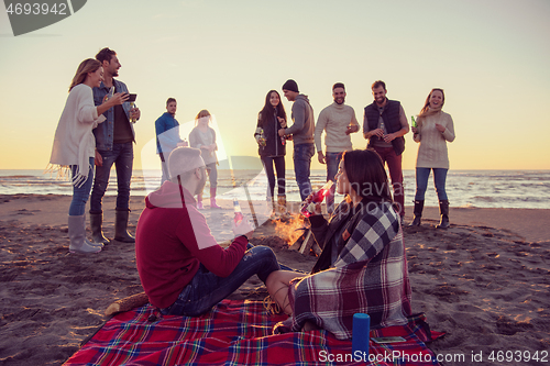 Image of Couple enjoying with friends at sunset on the beach