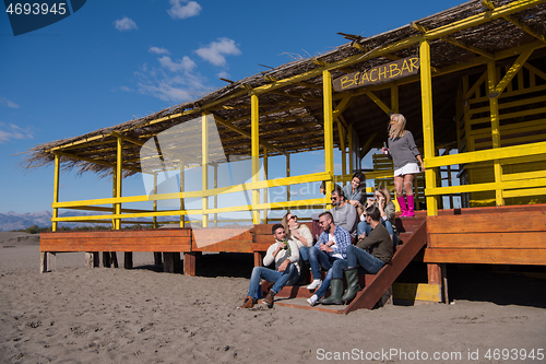 Image of Group of friends having fun on autumn day at beach