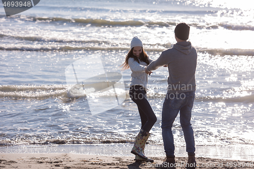 Image of Loving young couple on a beach at autumn sunny day