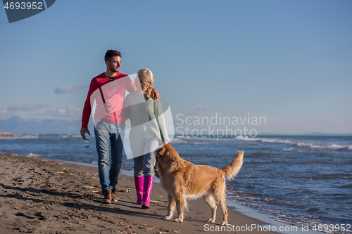 Image of couple with dog having fun on beach on autmun day