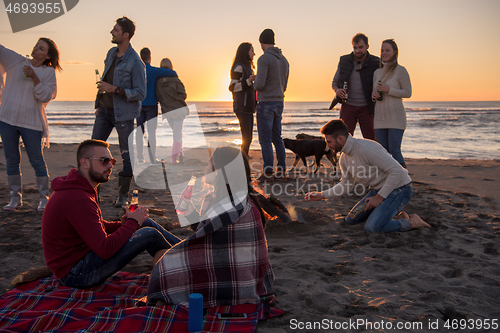 Image of Couple enjoying with friends at sunset on the beach