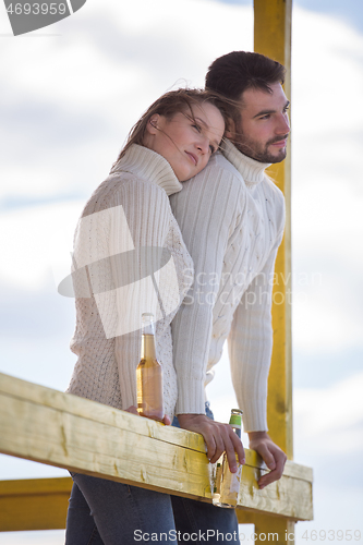 Image of young couple drinking beer together at the beach