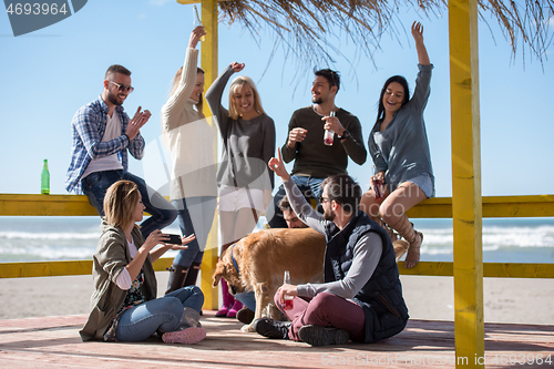 Image of Group of friends having fun on autumn day at beach