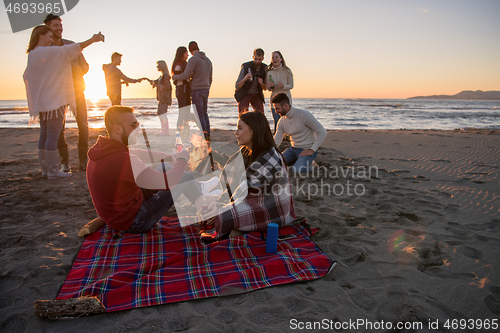 Image of Couple enjoying with friends at sunset on the beach