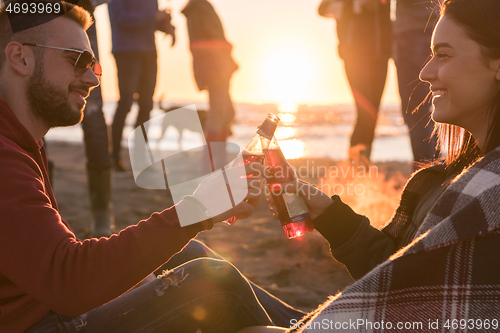 Image of Couple enjoying with friends at sunset on the beach