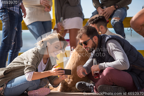 Image of Group of friends having fun on autumn day at beach