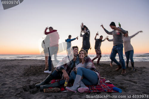 Image of Couple enjoying with friends at sunset on the beach