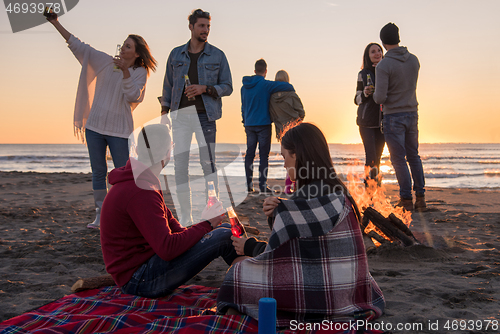 Image of Couple enjoying with friends at sunset on the beach