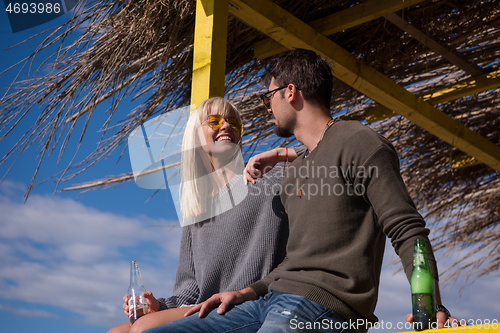 Image of young couple drinking beer together at the beach