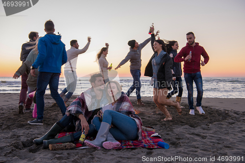 Image of Couple enjoying with friends at sunset on the beach