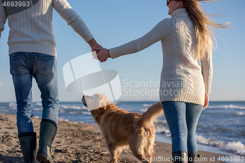 Image of couple with dog having fun on beach on autmun day