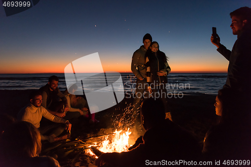 Image of Friends having fun at beach on autumn day