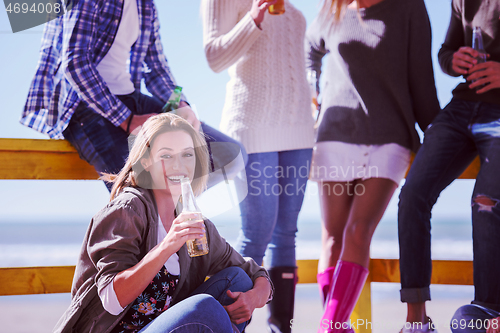 Image of Group of friends having fun on autumn day at beach