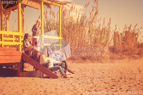 Image of Group of friends having fun on autumn day at beach