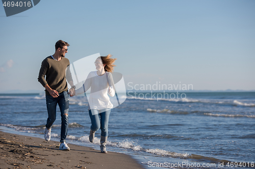 Image of Loving young couple on a beach at autumn sunny day