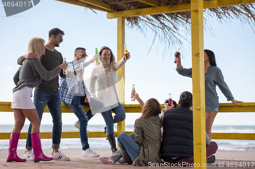 Image of Group of friends having fun on autumn day at beach