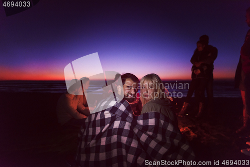 Image of Couple enjoying with friends at sunset on the beach