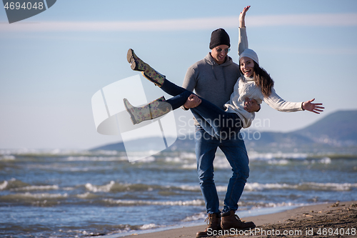 Image of Loving young couple on a beach at autumn sunny day