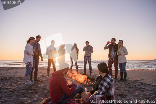 Image of Couple enjoying with friends at sunset on the beach