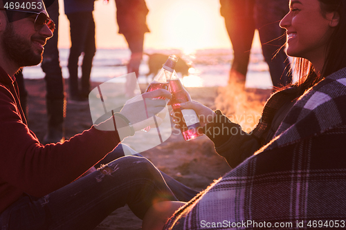 Image of Couple enjoying with friends at sunset on the beach