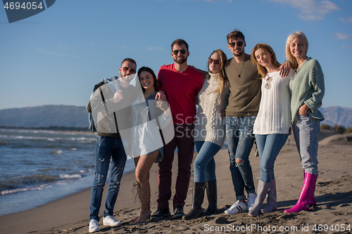 Image of portrait of friends having fun on beach during autumn day