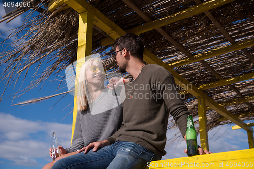 Image of young couple drinking beer together at the beach