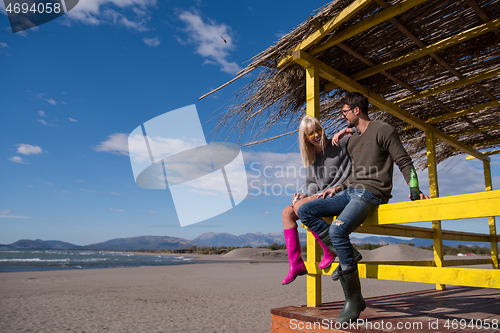 Image of young couple drinking beer together at the beach