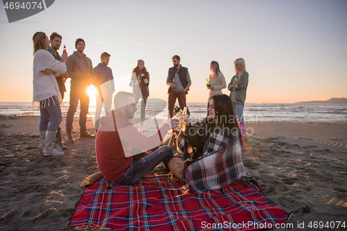 Image of Couple enjoying with friends at sunset on the beach