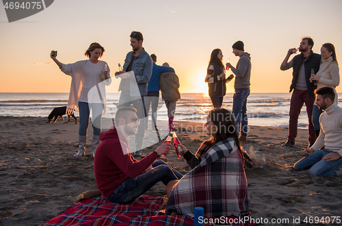 Image of Couple enjoying with friends at sunset on the beach