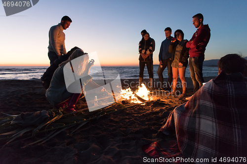 Image of Friends having fun at beach on autumn day