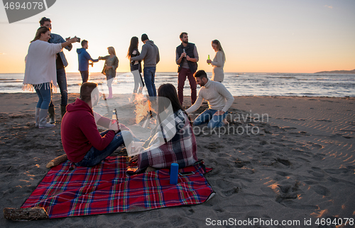 Image of Couple enjoying with friends at sunset on the beach