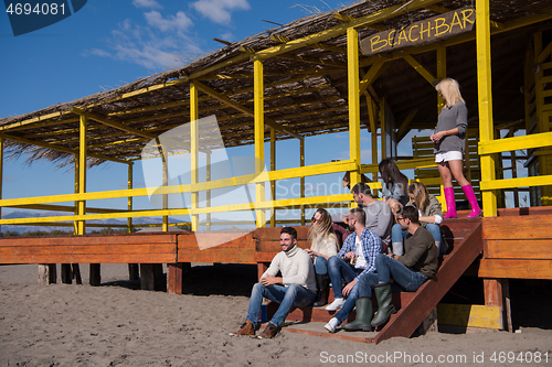 Image of Group of friends having fun on autumn day at beach