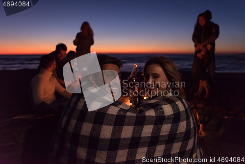 Image of Couple enjoying with friends at sunset on the beach