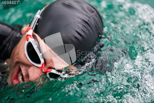 Image of triathlon athlete swimming on lake wearing wetsuit